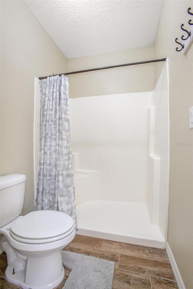 bathroom featuring a shower with curtain, a textured ceiling, and toilet