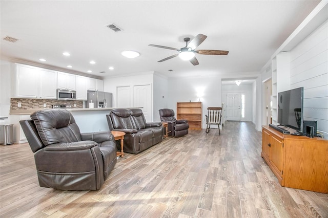 living room featuring ornamental molding, ceiling fan, and light wood-type flooring