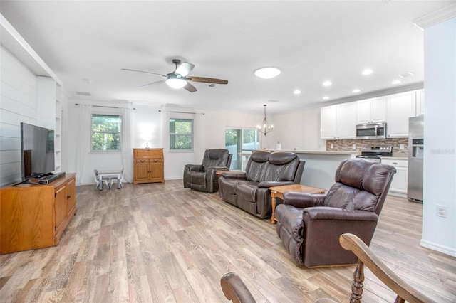 living room with ceiling fan with notable chandelier and light wood-type flooring