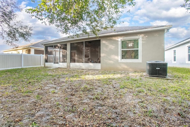 rear view of house with cooling unit, a sunroom, and a lawn