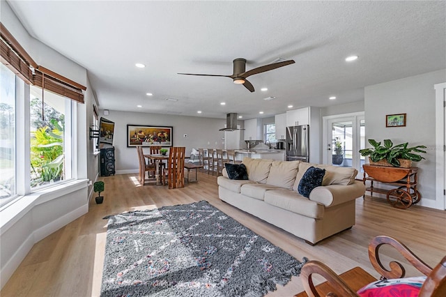 living room with ceiling fan, a wealth of natural light, and light wood-type flooring