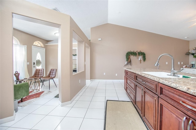 interior space featuring lofted ceiling, sink, light stone countertops, and light tile patterned flooring