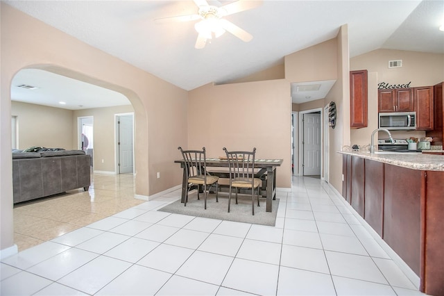 tiled dining area with ceiling fan and lofted ceiling