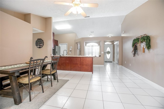 tiled dining room featuring lofted ceiling, sink, a textured ceiling, and ceiling fan