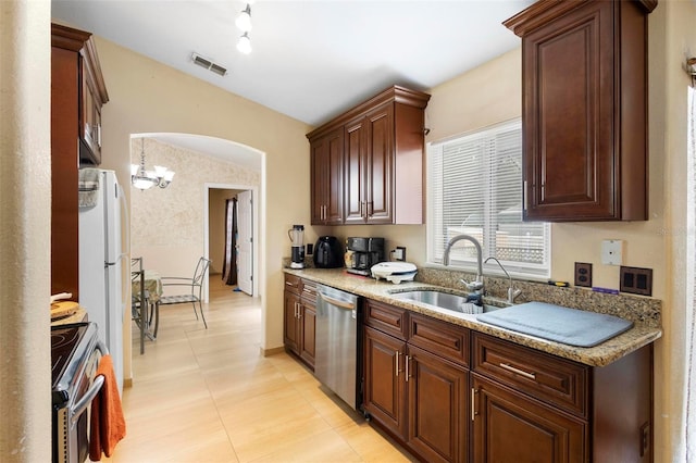 kitchen with an inviting chandelier, sink, light stone countertops, and appliances with stainless steel finishes