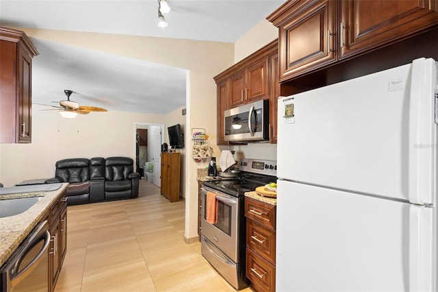 kitchen featuring light tile patterned flooring, sink, light stone counters, appliances with stainless steel finishes, and ceiling fan