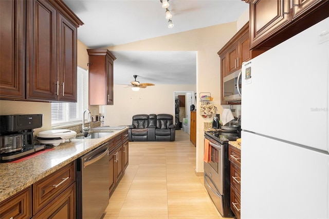 kitchen with light tile patterned flooring, sink, ceiling fan, stainless steel appliances, and light stone countertops