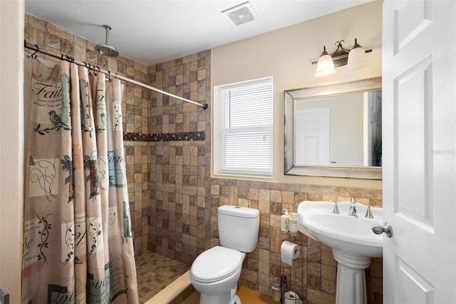 bathroom with walk in shower, toilet, and tile walls