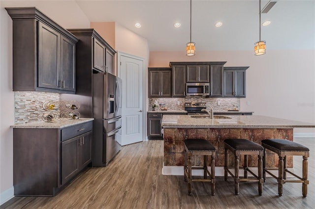 kitchen featuring light stone countertops, stainless steel appliances, and hanging light fixtures