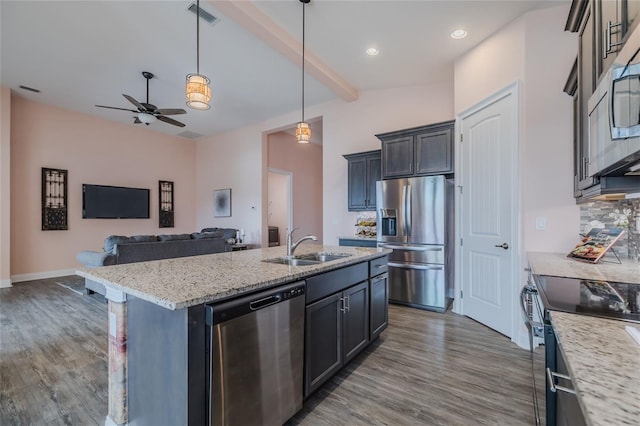 kitchen with an island with sink, decorative light fixtures, light stone countertops, dark wood-type flooring, and appliances with stainless steel finishes