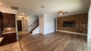 unfurnished living room with crown molding, ceiling fan, and dark hardwood / wood-style flooring