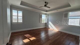 empty room featuring crown molding, dark wood-type flooring, and a tray ceiling