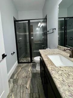 bathroom featuring vanity, toilet, and a shower with shower door