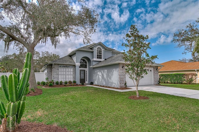 traditional-style house with a garage, driveway, brick siding, and a front yard