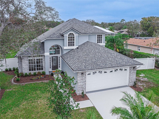 traditional-style home with a garage, driveway, fence, and brick siding