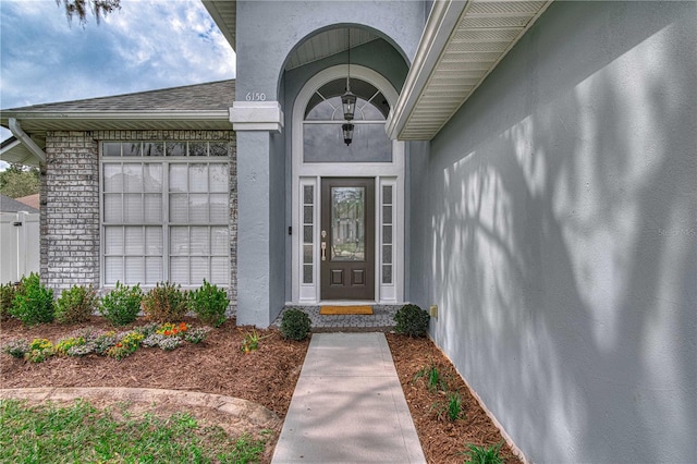 doorway to property featuring brick siding and stucco siding