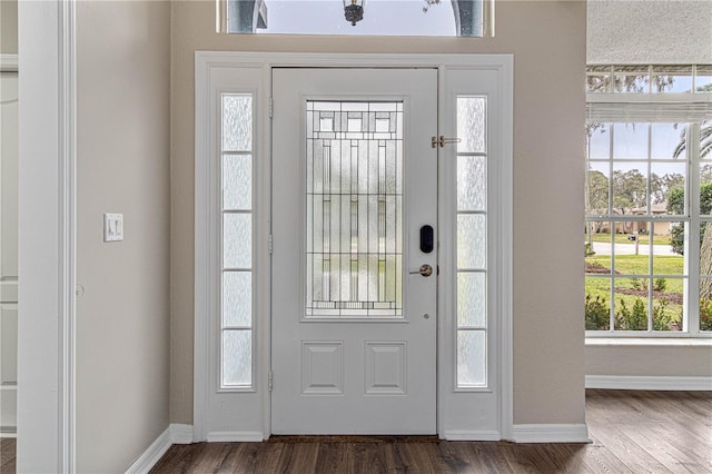 foyer with dark wood-style floors and baseboards