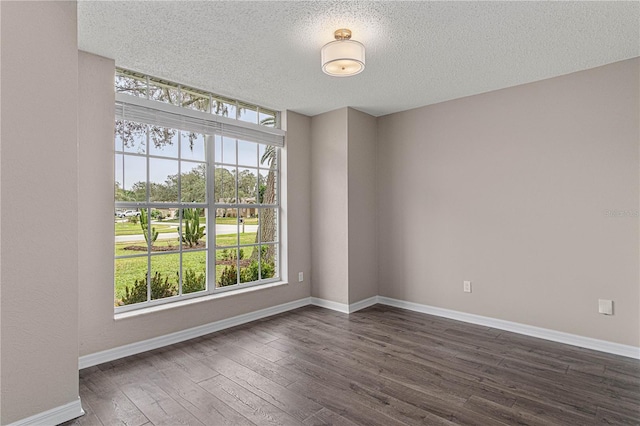 empty room featuring dark wood-style flooring, a textured ceiling, and baseboards