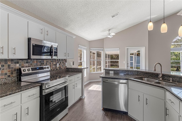 kitchen featuring vaulted ceiling, appliances with stainless steel finishes, white cabinets, and a sink