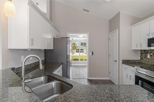 kitchen with dark stone countertops, a sink, visible vents, and white cabinetry