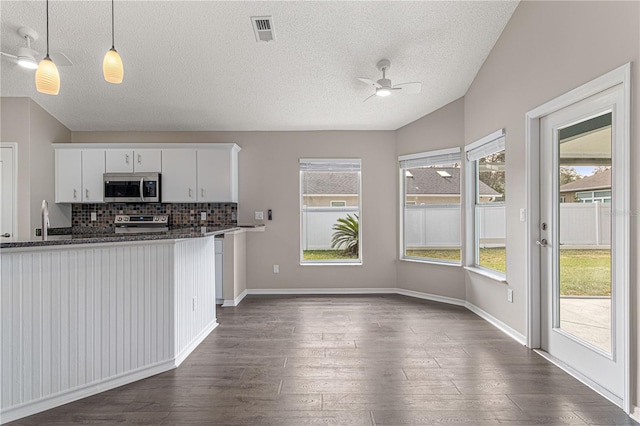 kitchen featuring stainless steel appliances, visible vents, white cabinetry, dark stone countertops, and pendant lighting