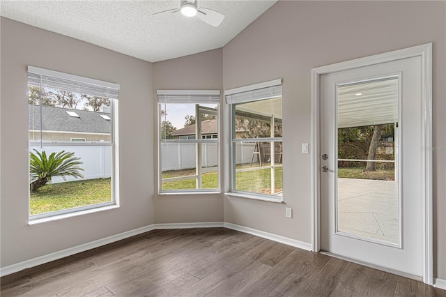 entryway with lofted ceiling, a textured ceiling, wood finished floors, and baseboards