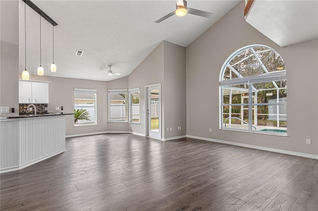 unfurnished living room with baseboards, visible vents, dark wood finished floors, and a ceiling fan