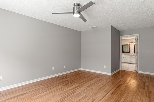 unfurnished bedroom with a textured ceiling, a ceiling fan, visible vents, baseboards, and light wood finished floors