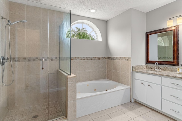 bathroom featuring a stall shower, a textured ceiling, vanity, a whirlpool tub, and tile patterned floors