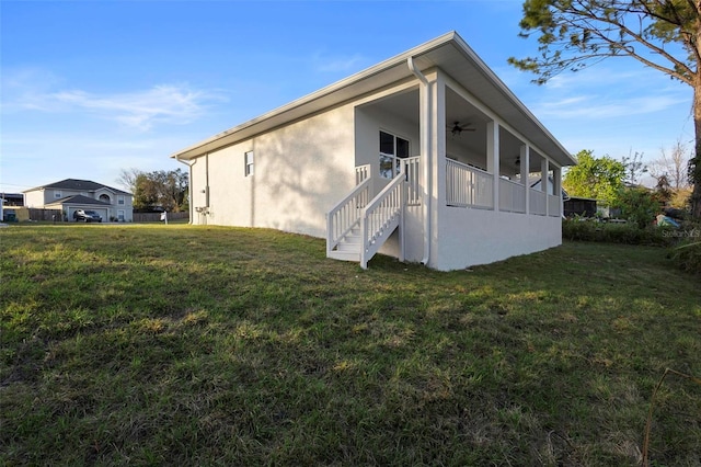 view of side of home featuring a lawn, a ceiling fan, and stucco siding