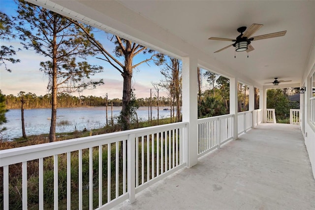 patio terrace at dusk with a water view and ceiling fan