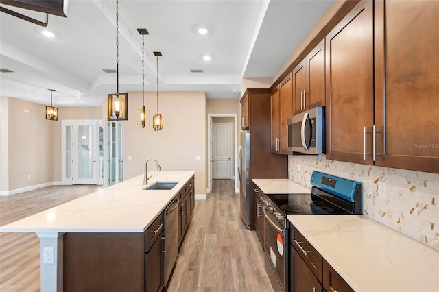 kitchen with light wood-style flooring, a sink, appliances with stainless steel finishes, backsplash, and pendant lighting