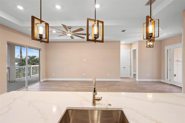 kitchen with open floor plan, hanging light fixtures, light stone counters, and visible vents