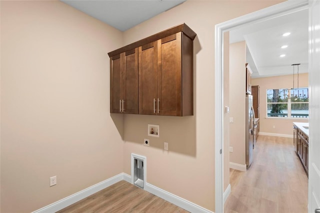 laundry room featuring hookup for a washing machine, cabinet space, electric dryer hookup, light wood-type flooring, and baseboards