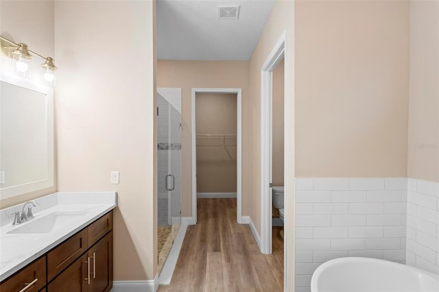 bathroom featuring toilet, vanity, visible vents, a soaking tub, and a shower stall