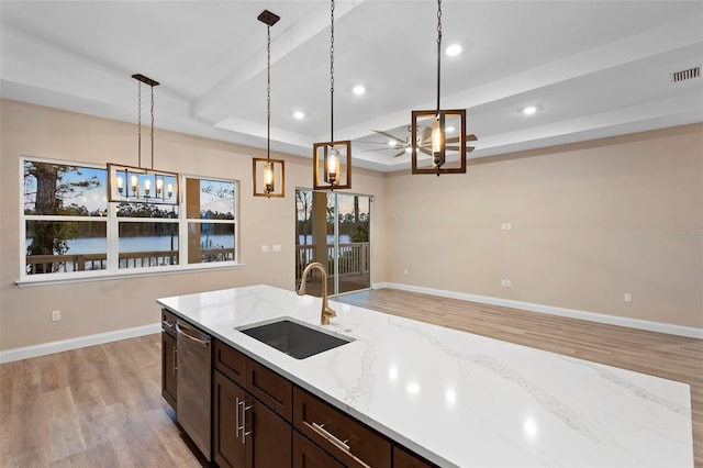 kitchen featuring baseboards, dishwasher, light stone countertops, pendant lighting, and a sink