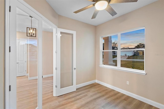 spare room with light wood-type flooring, ceiling fan, and baseboards