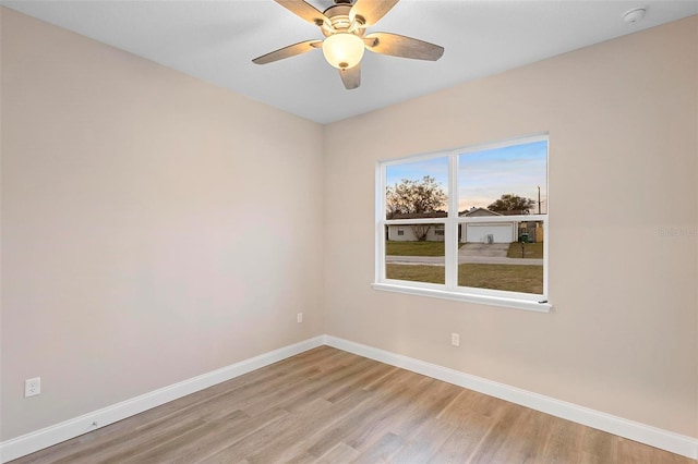 empty room featuring light wood-style floors, a ceiling fan, and baseboards