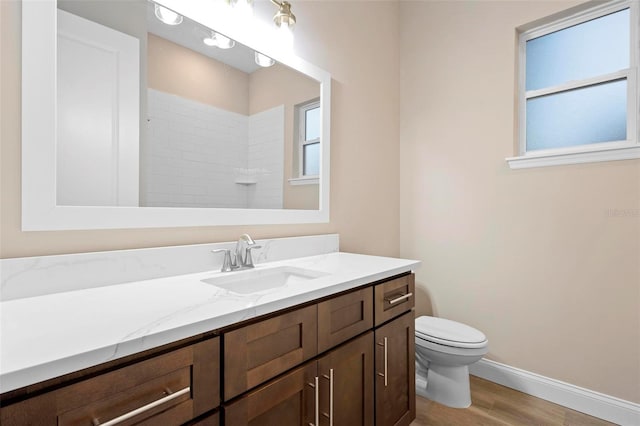 full bathroom featuring toilet, wood finished floors, vanity, baseboards, and walk in shower