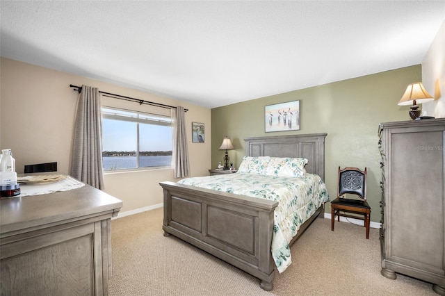 bedroom featuring light colored carpet and a water view