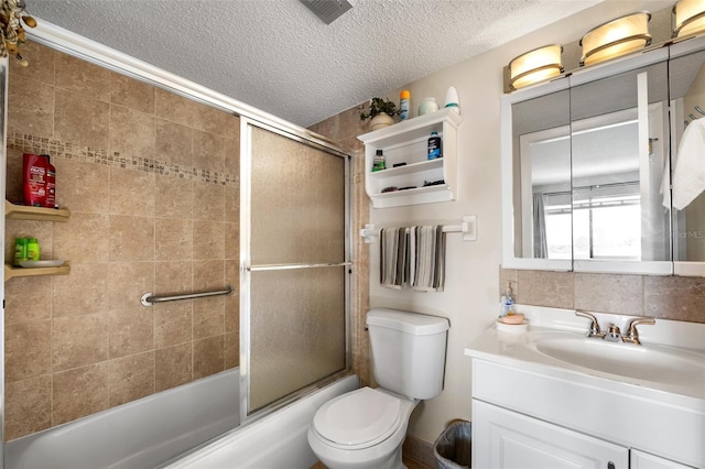 full bathroom featuring bath / shower combo with glass door, vanity, a textured ceiling, and toilet