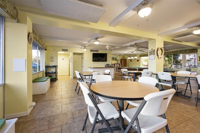 tiled dining room with ceiling fan, beamed ceiling, and a healthy amount of sunlight