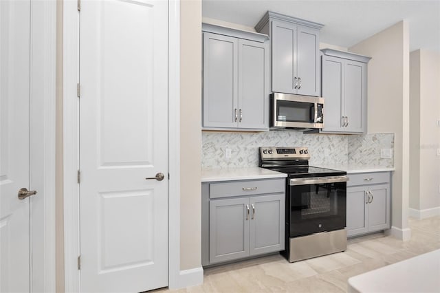 kitchen featuring appliances with stainless steel finishes, gray cabinets, and backsplash