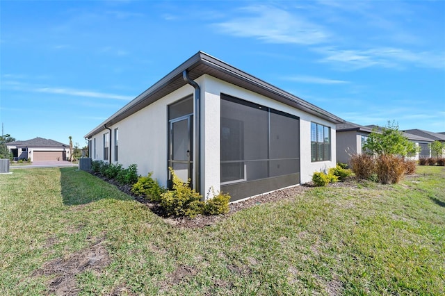 view of home's exterior featuring a sunroom, central AC unit, and a lawn