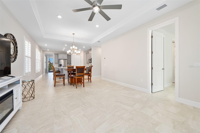 dining space with crown molding, a tray ceiling, and ceiling fan with notable chandelier