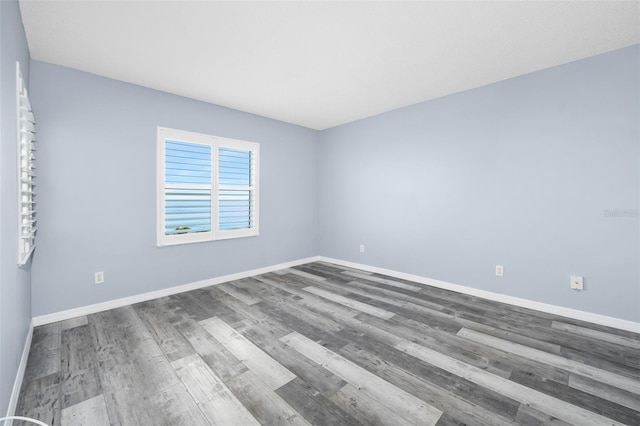 spare room featuring baseboards and wood finished floors