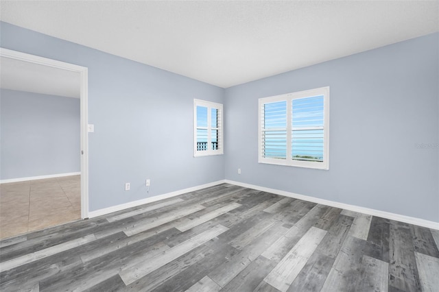 spare room featuring baseboards and wood finished floors