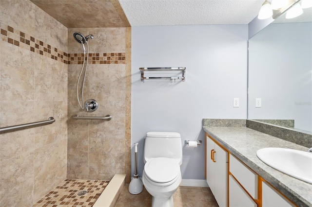 bathroom featuring a tile shower, vanity, toilet, and a textured ceiling