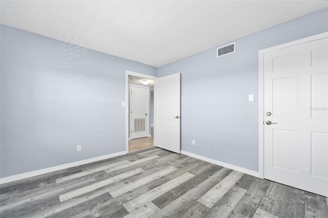 unfurnished bedroom featuring baseboards, visible vents, and wood finished floors