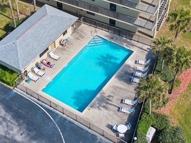 community pool with a patio area and fence